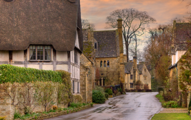 View of a quaint coutryside street in the cotswolds with thatched-rooved cottages and houses build with cotswold stone