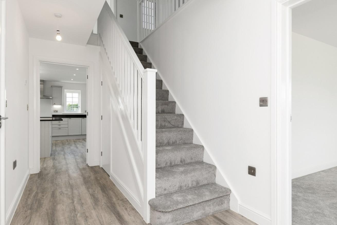 A spacious hallway with wooden flooring and stairs leading up to the first floor