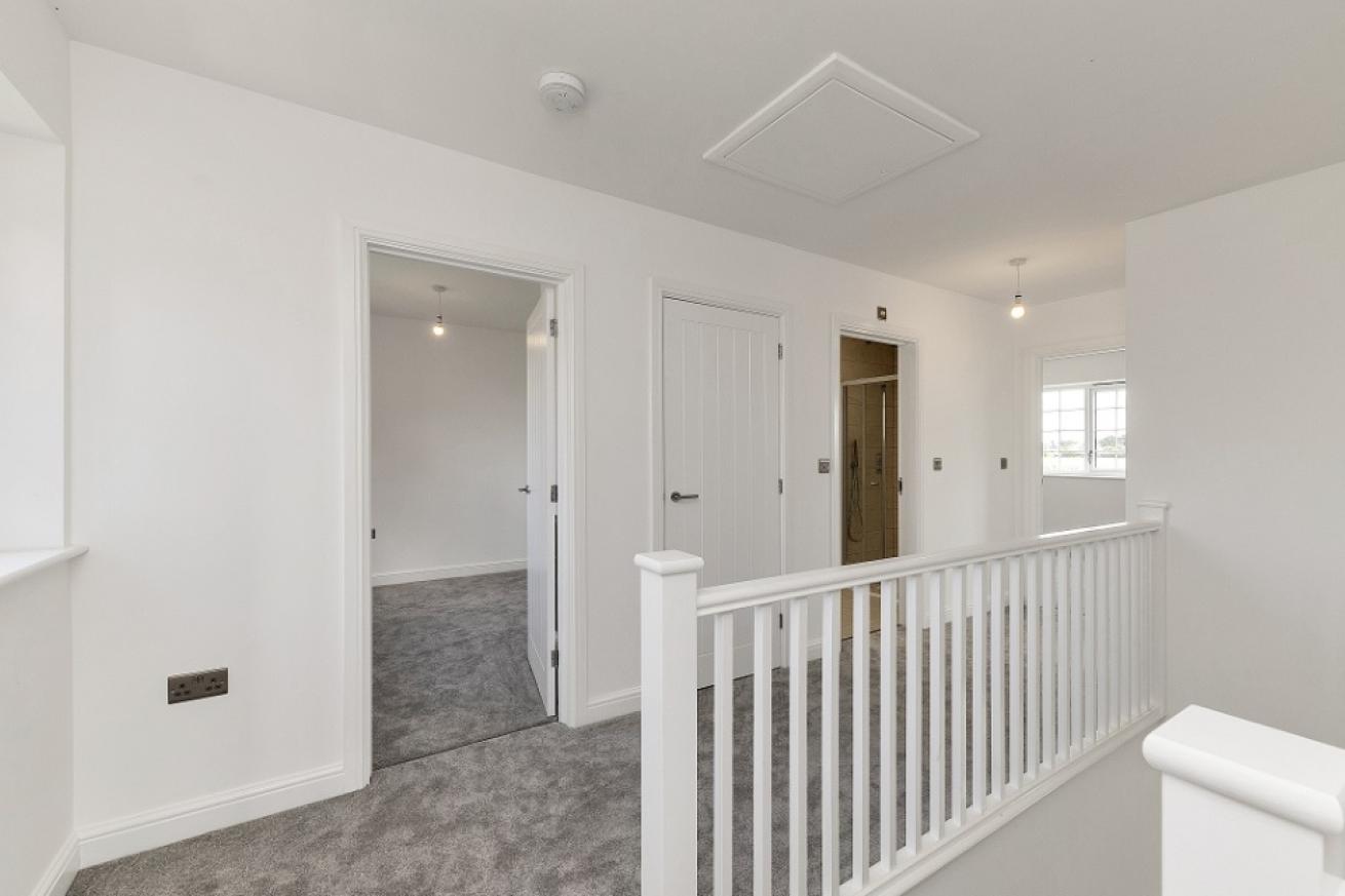 A first storey landing all decorated white with grey carpers with doorways to multiple bedrooms